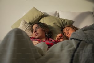 a couple of women laying in bed next to each other