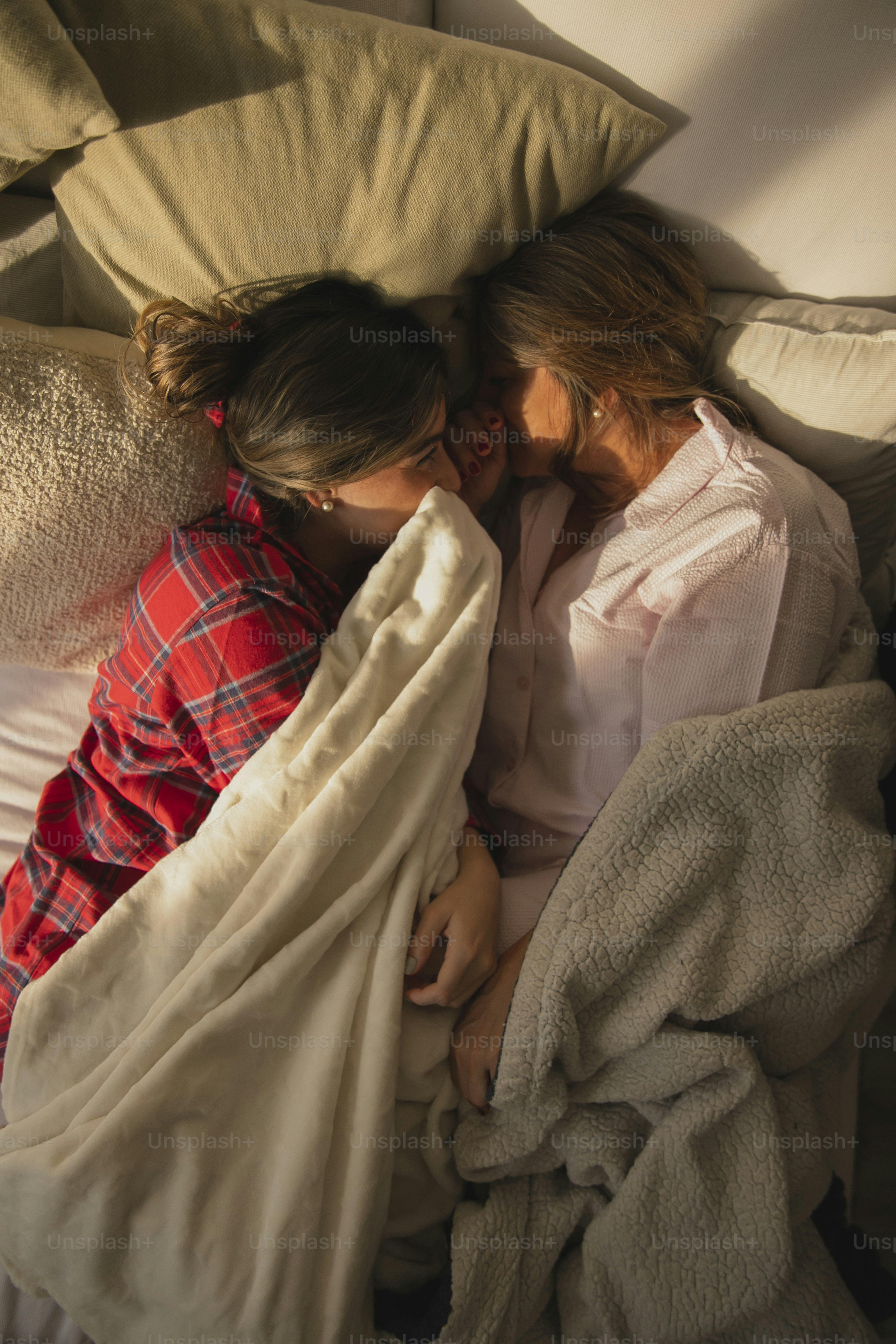 Un par de mujeres acostadas una al lado de la otra en una cama