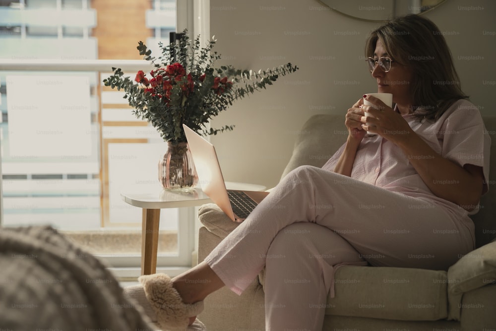 uma mulher sentada em um sofá bebendo uma xícara de café
