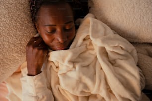 a woman laying on top of a bed under a blanket