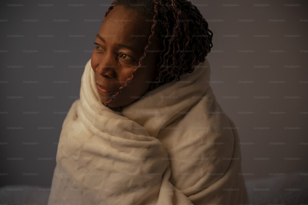uma mulher enrolada em um cobertor com os olhos fechados