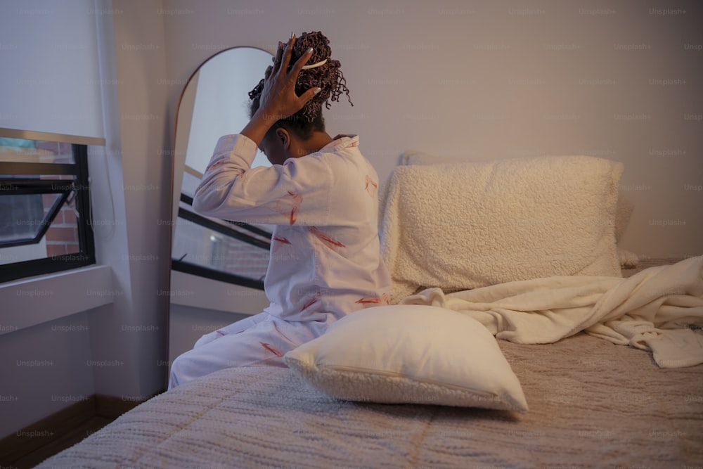 uma mulher sentada em cima de uma cama ao lado de travesseiros