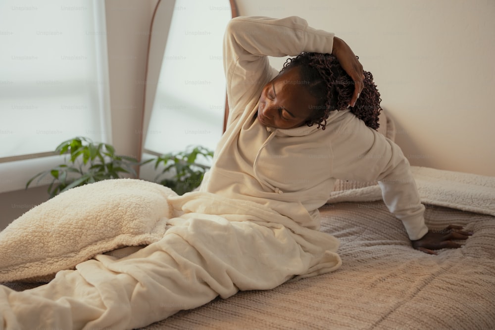a woman laying on top of a bed covered in a blanket