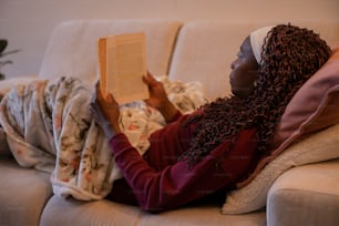 une femme assise sur un canapé lisant un livre