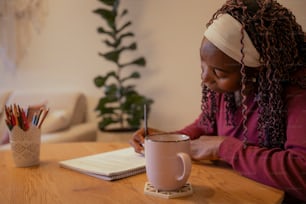 a woman sitting at a table writing in a notebook