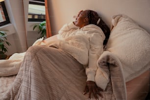 a woman laying on a bed with a blanket