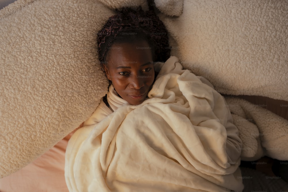 a woman wrapped up in a blanket on a bed