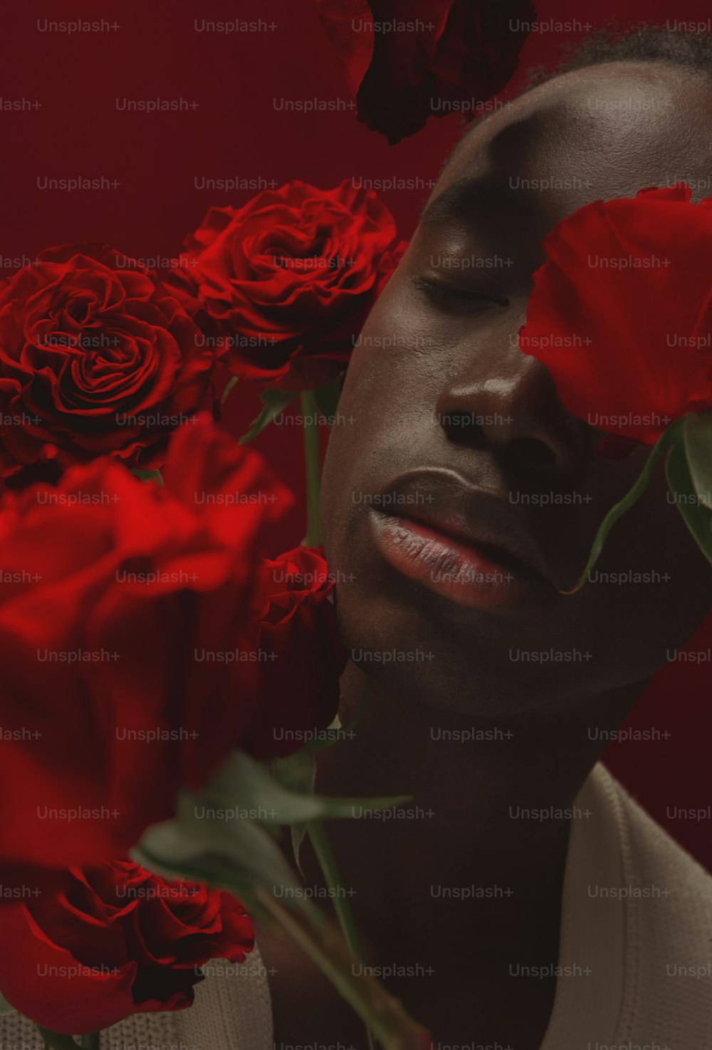 a man with his eyes closed with roses in front of him