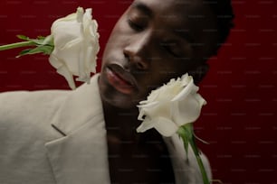 a man in a white suit holding a white rose