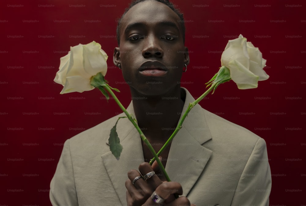 a man in a suit holding three white roses