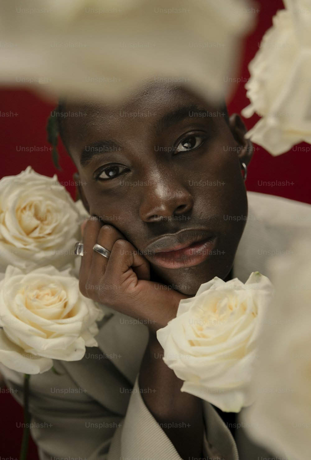 a man with a ring on his finger next to white roses