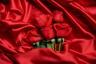um monte de rosas vermelhas deitadas sobre um pano vermelho
