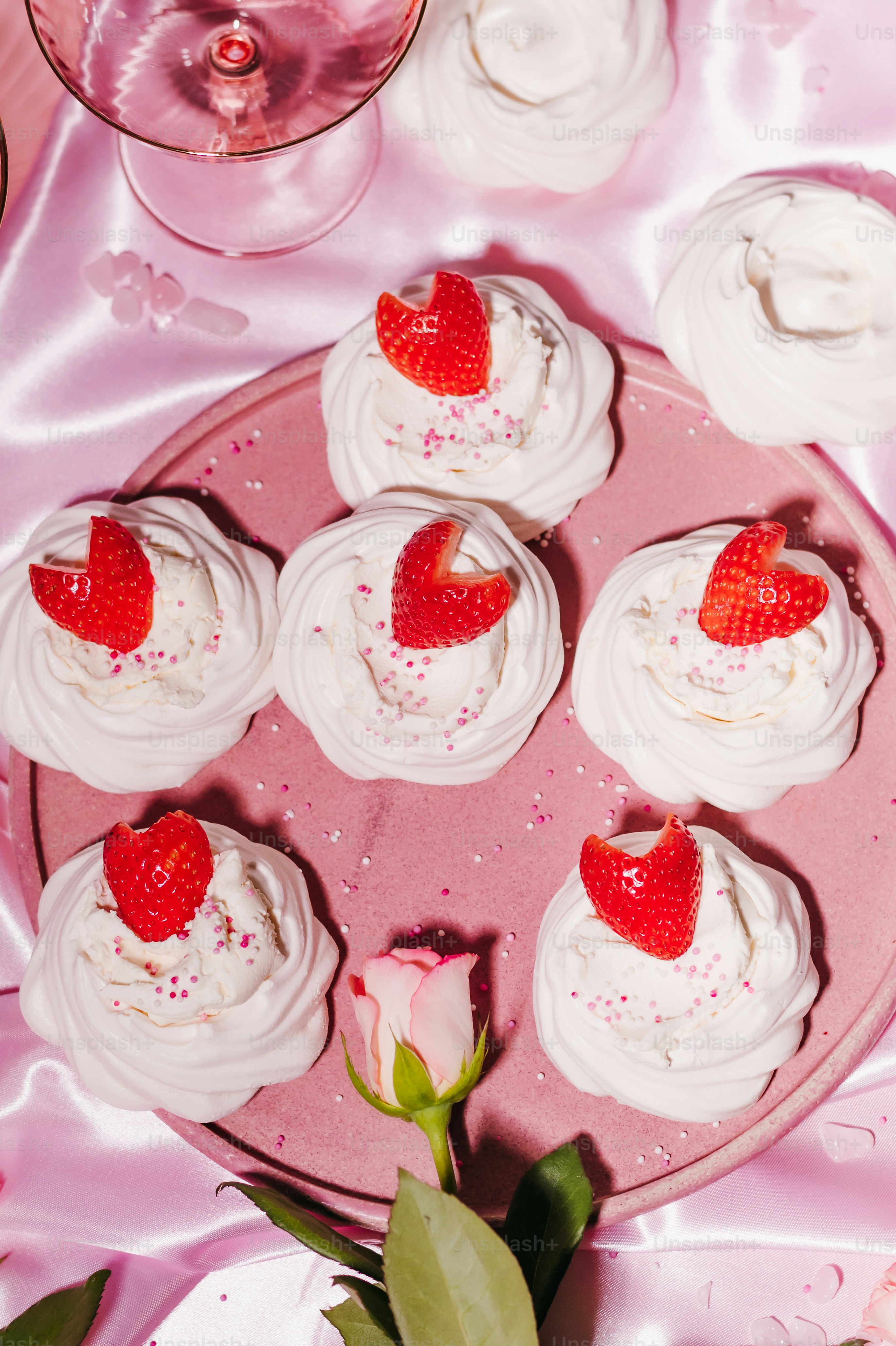A pink plate topped with cupcakes and strawberries
