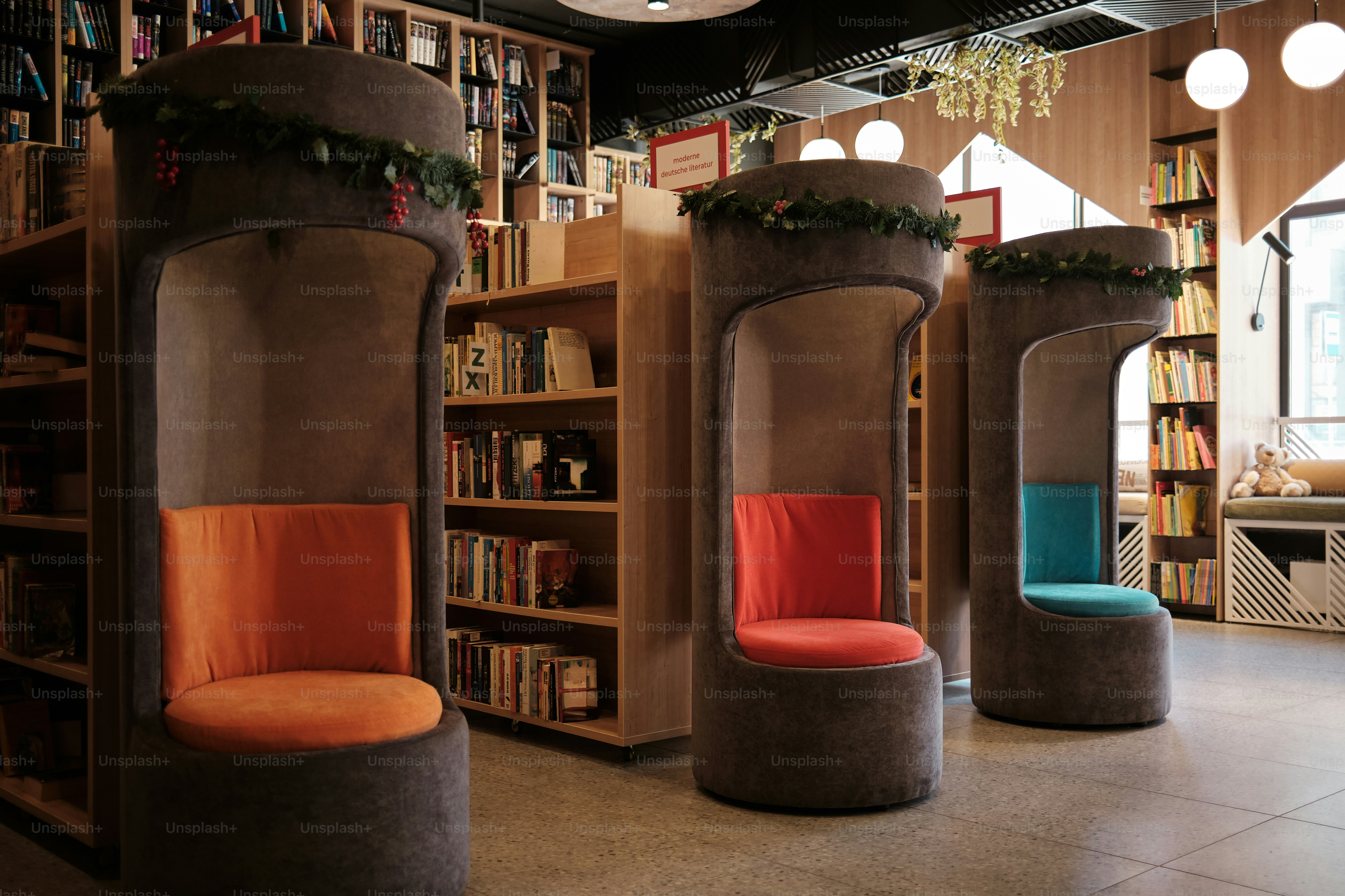 Three modern reading pods with colorful chairs in a library.