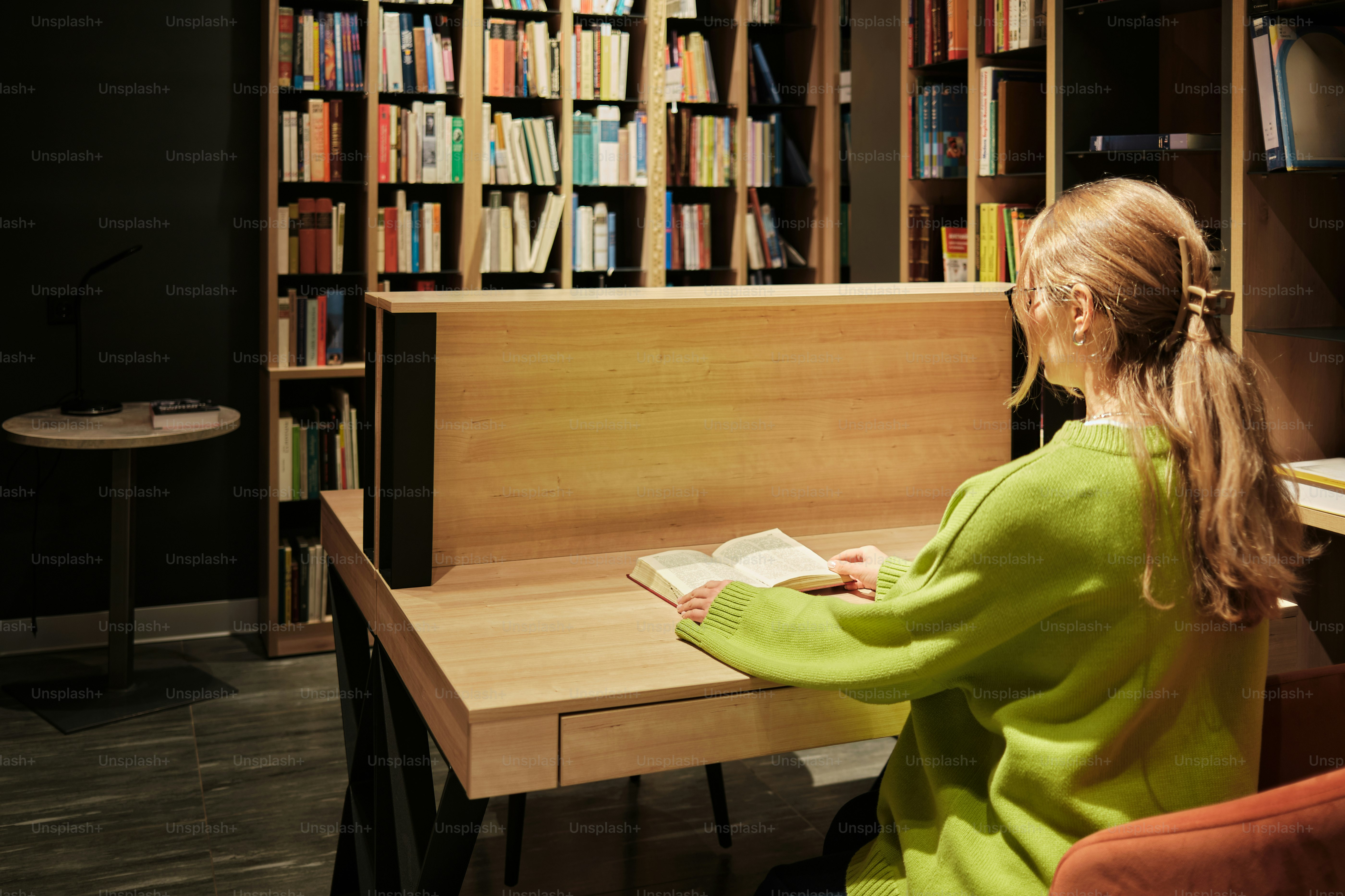 Femme lisant un livre à un bureau dans une bibliothèque.