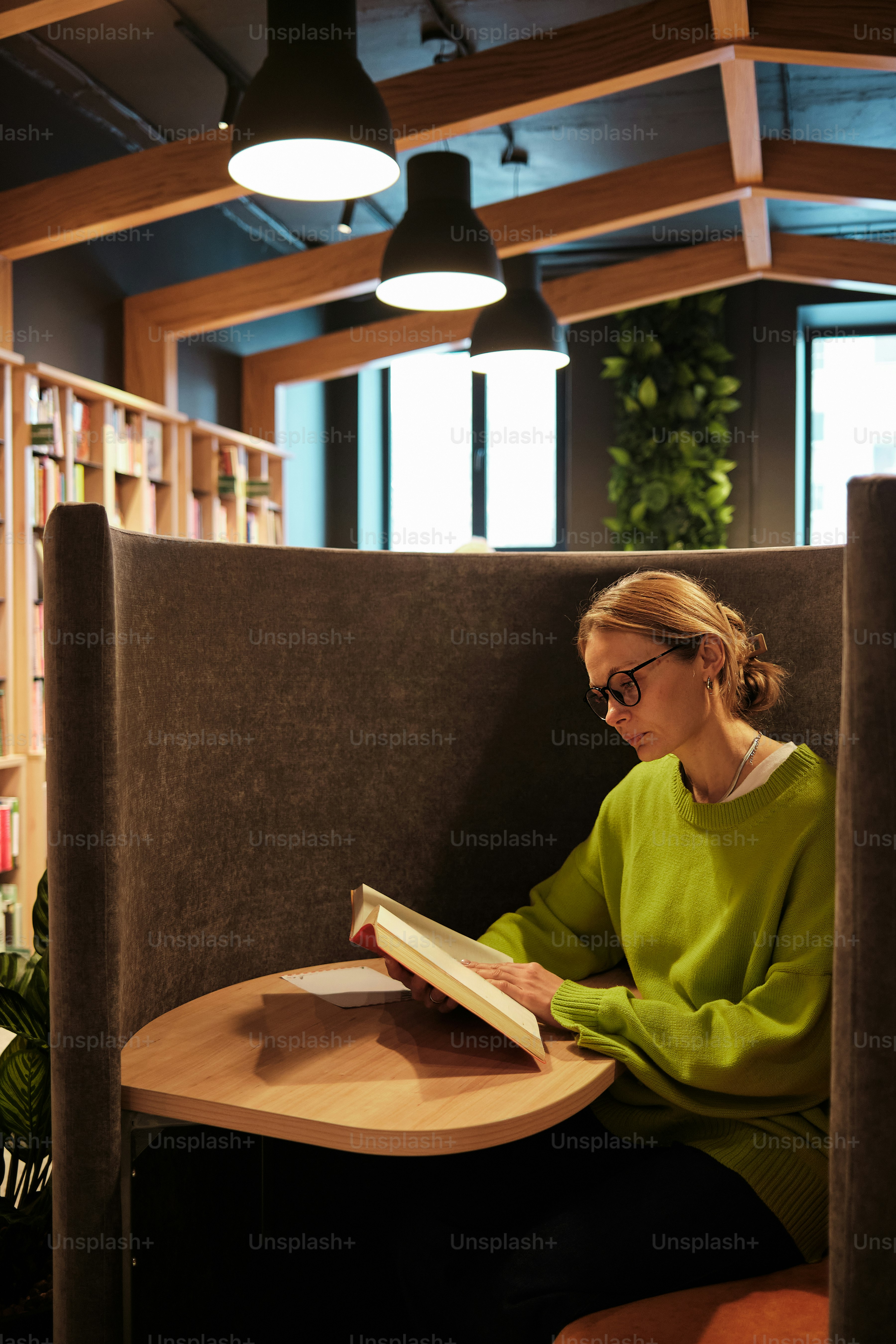 Frau, die in einer gemütlichen Arbeitsecke ein Buch liest