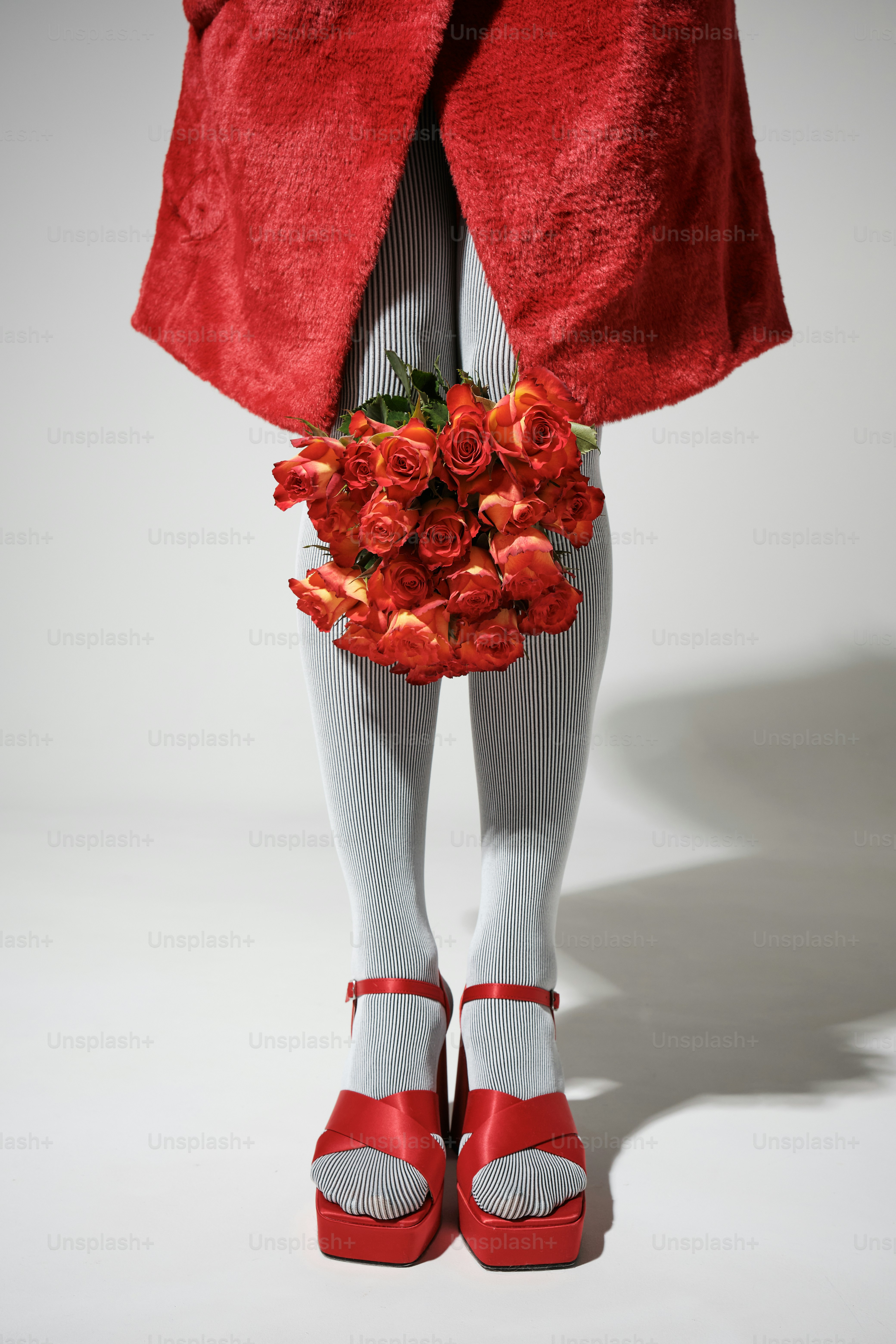 Woman in red coat holding bouquet of red roses