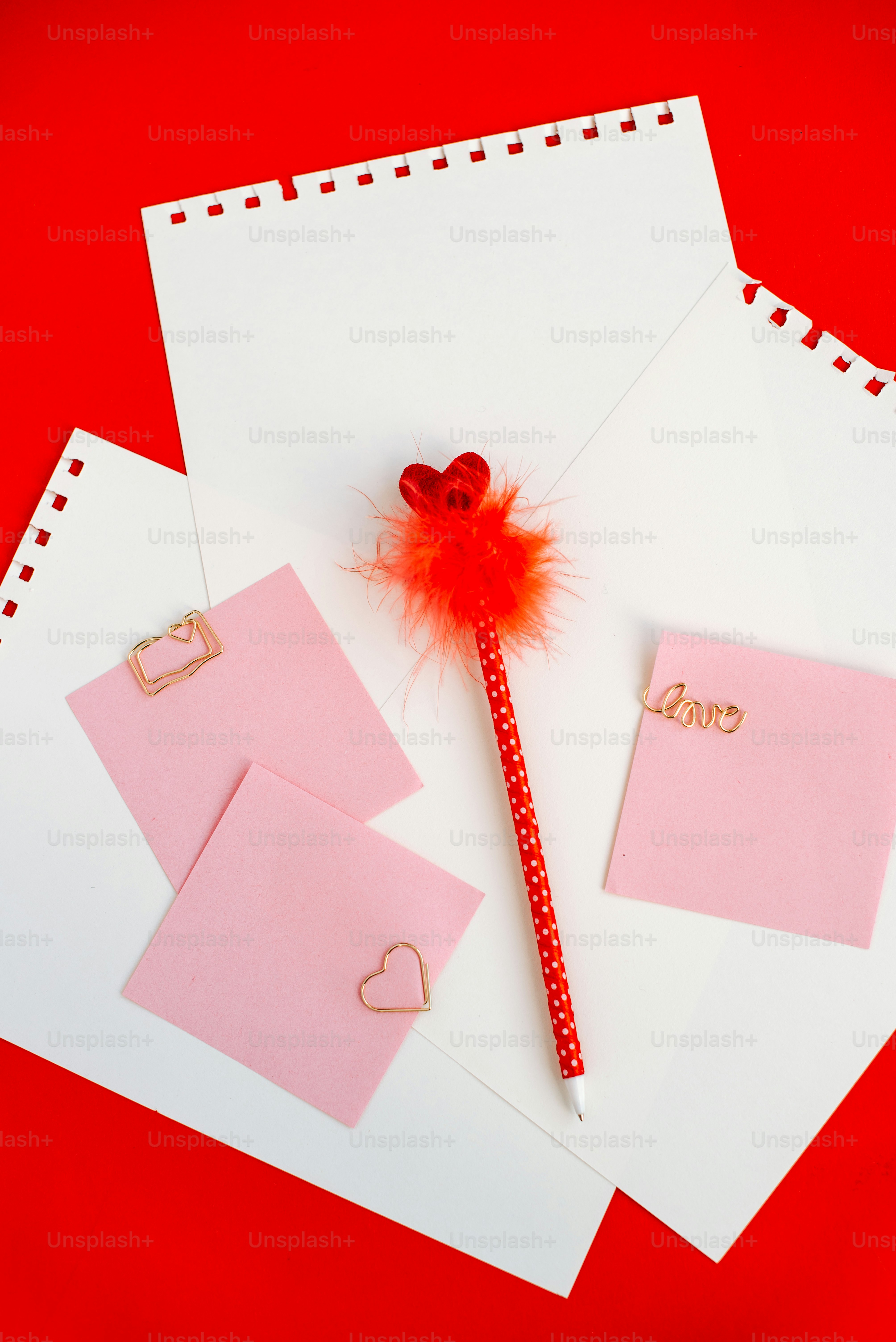 Valentine's day stationery with heart-shaped paper clips and pen.