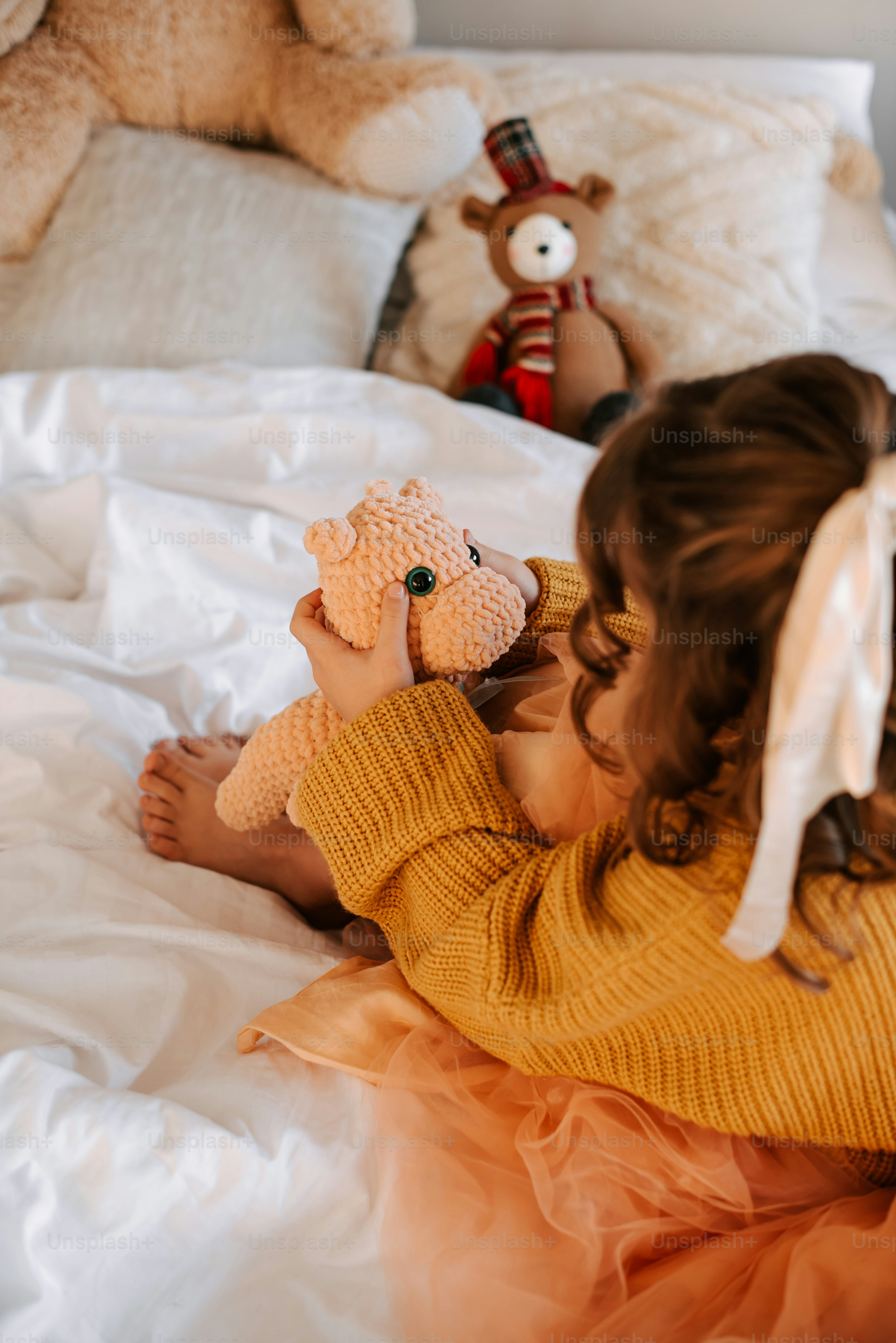 Child holding a stuffed hippo on a bed