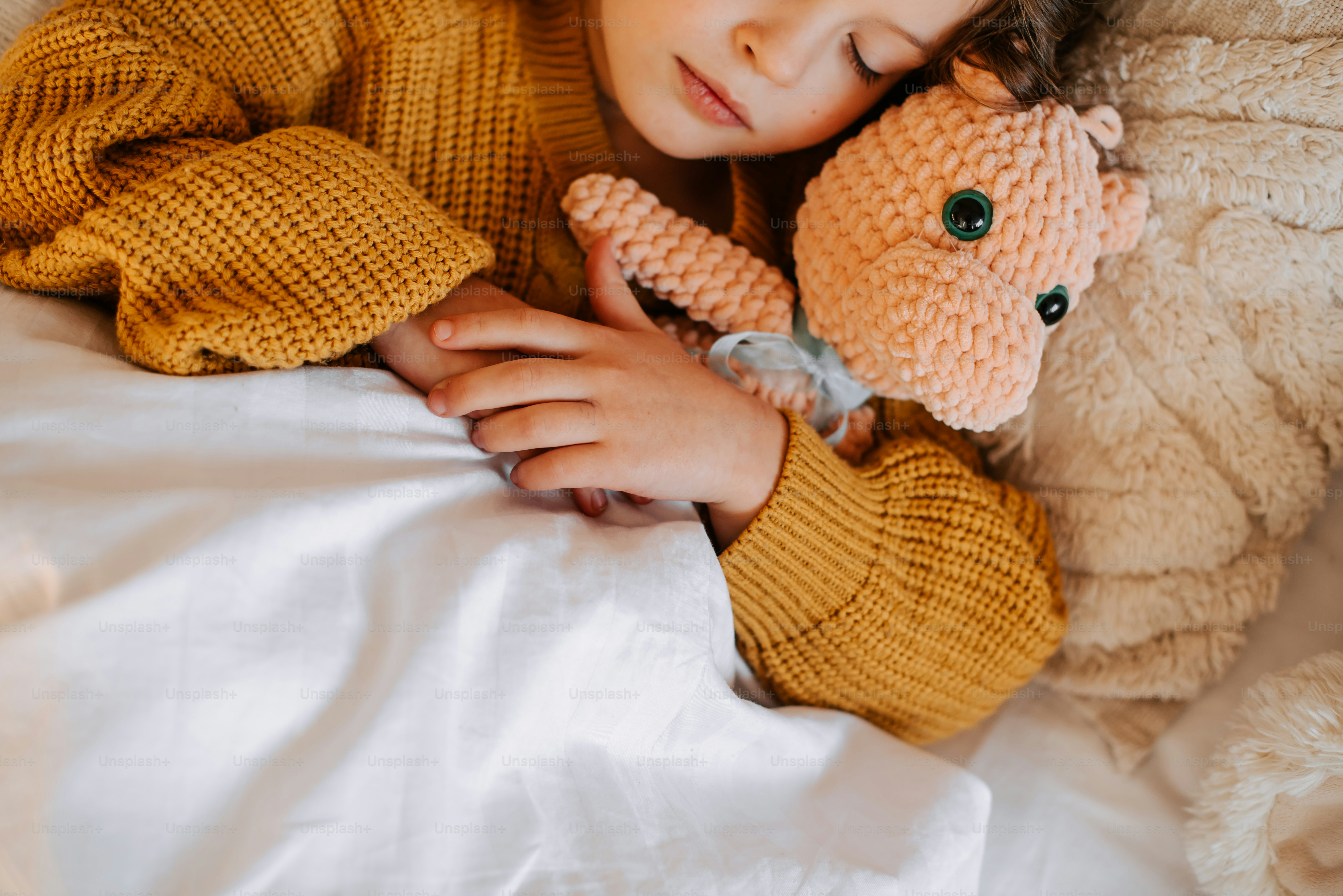 A young child sleeps peacefully with a stuffed toy.