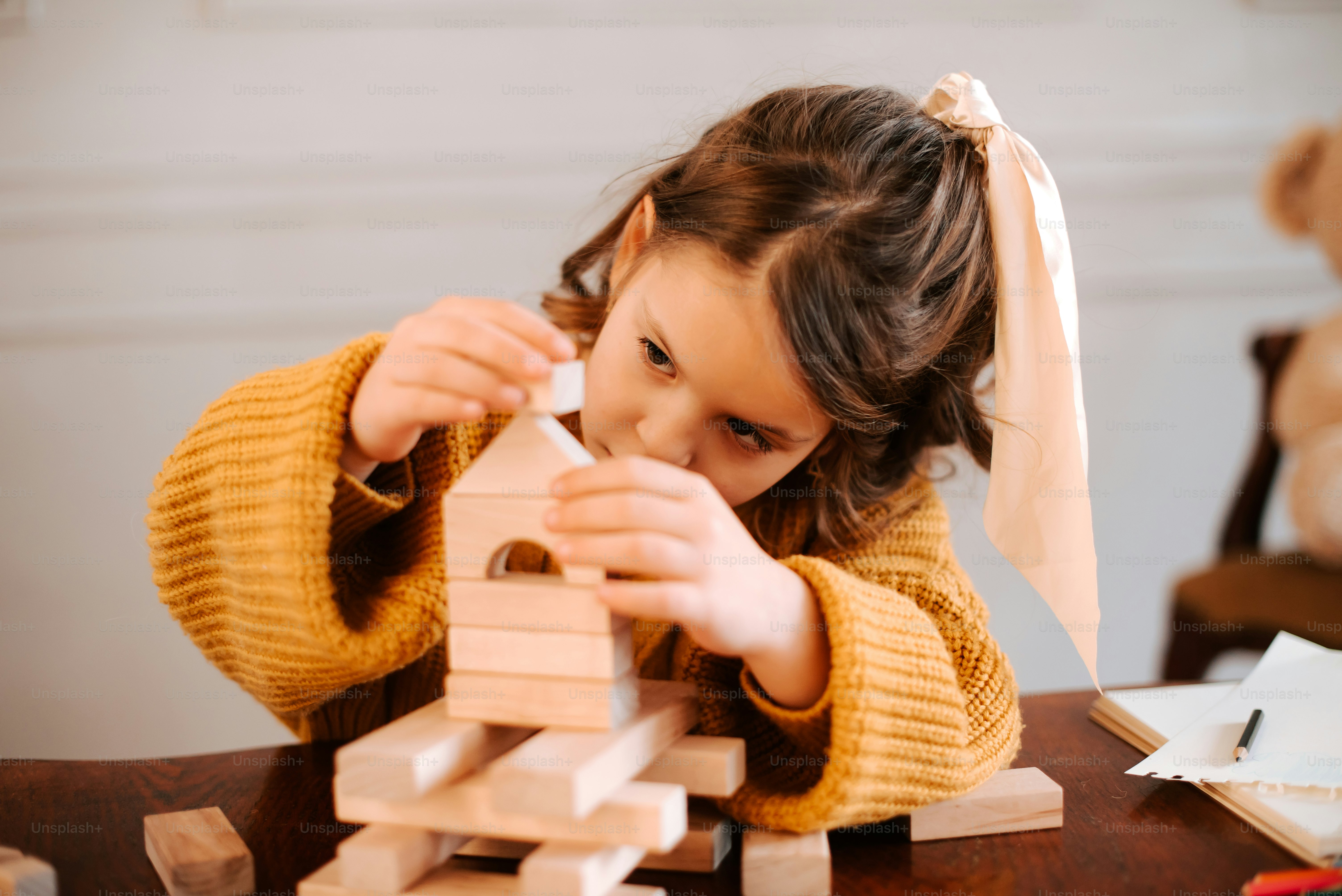 A young girl building a wooden tower with blocks
