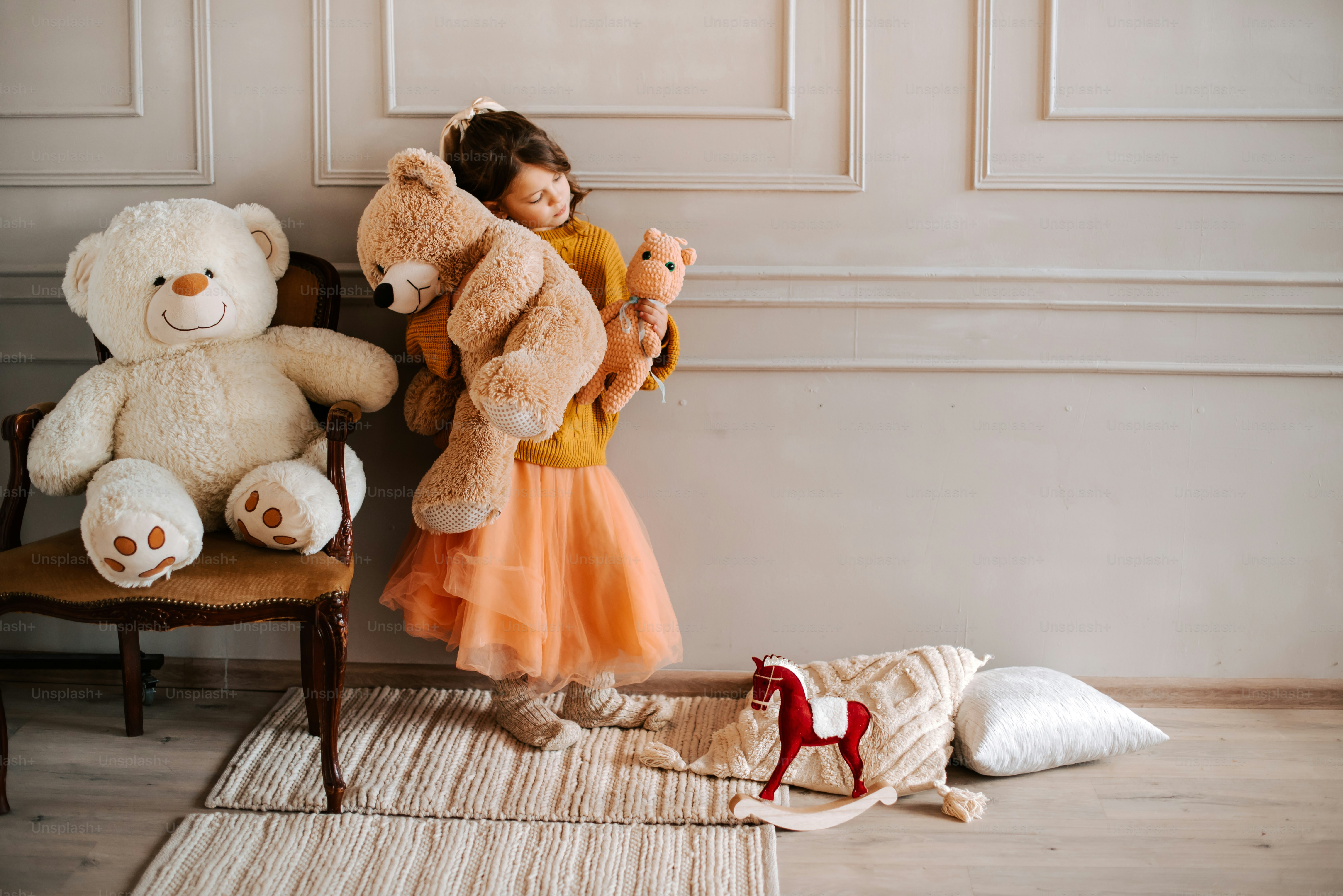 A young girl holds several stuffed animals and toys.