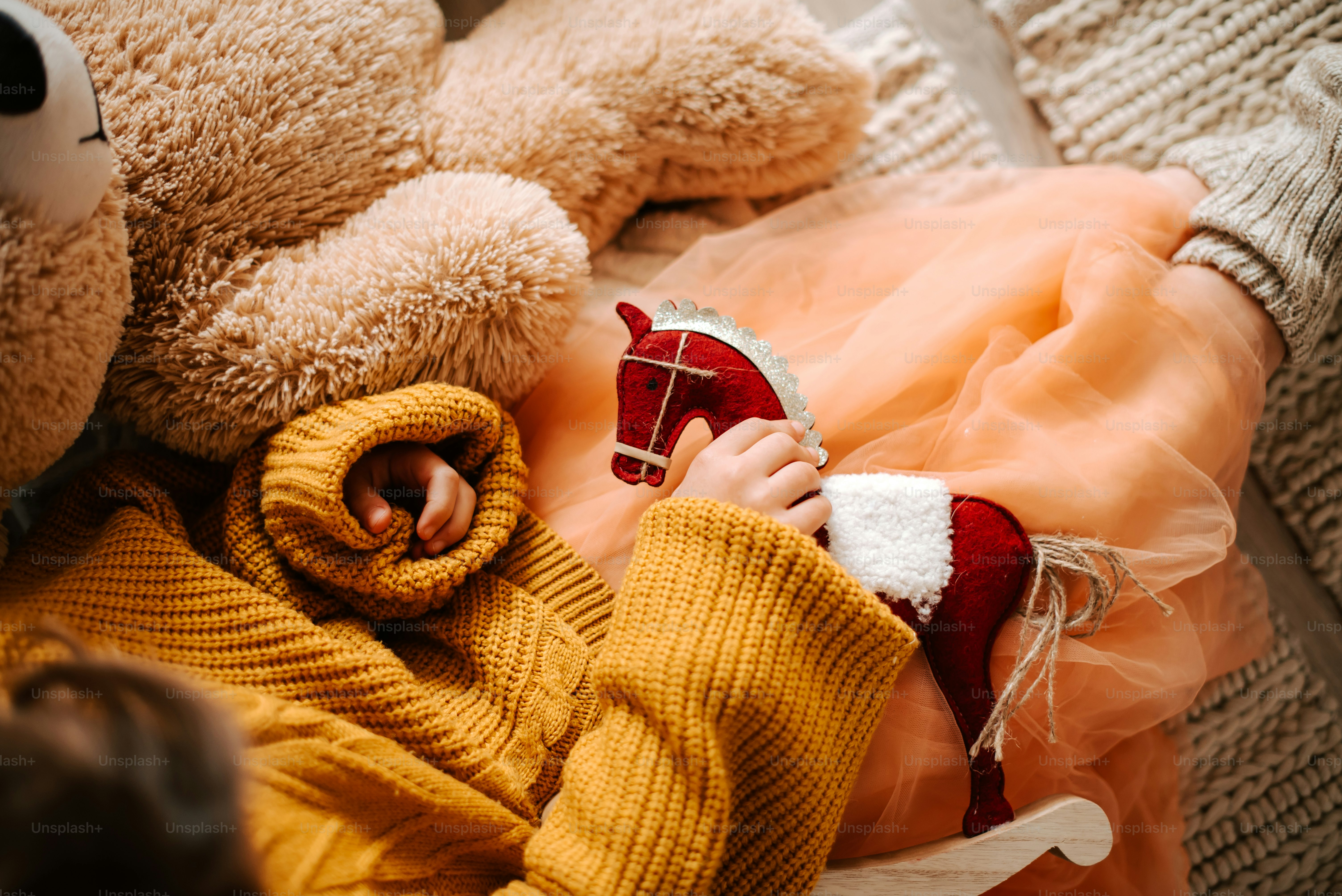 Child holding a small rocking horse toy.