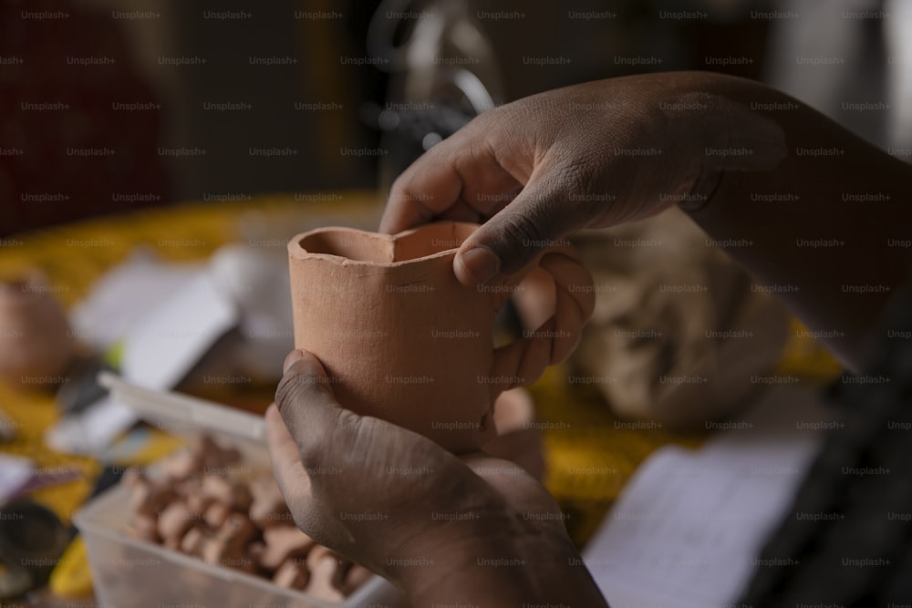 a person holding a clay pot over a container