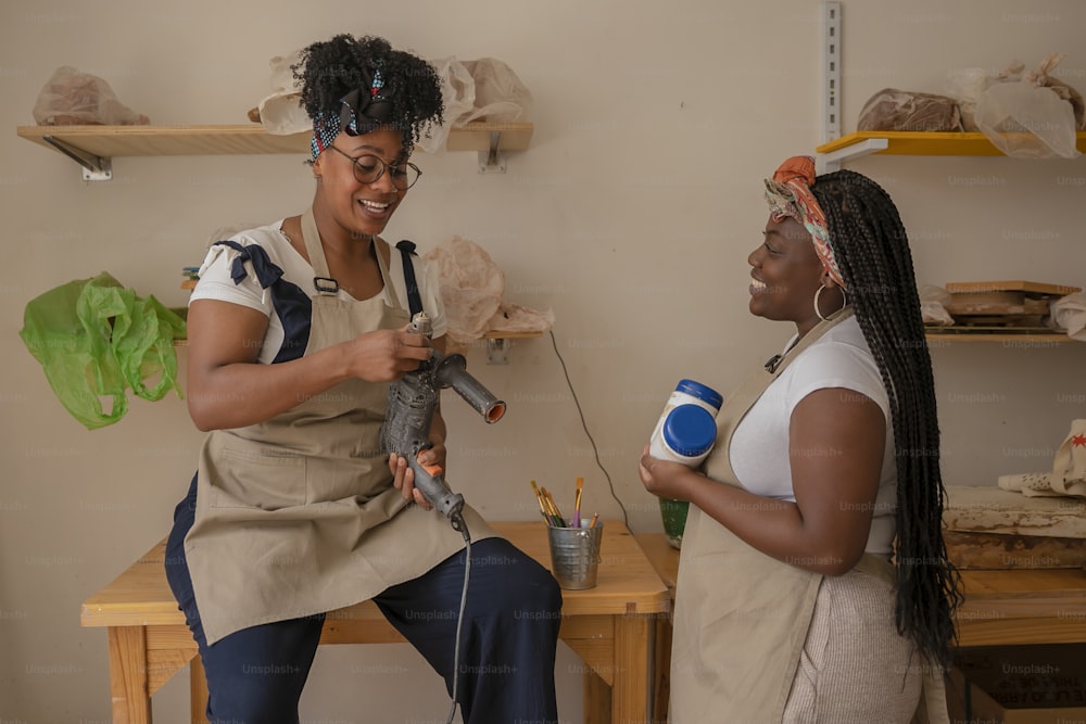 two women are smiling while one of them is using a hairdryer