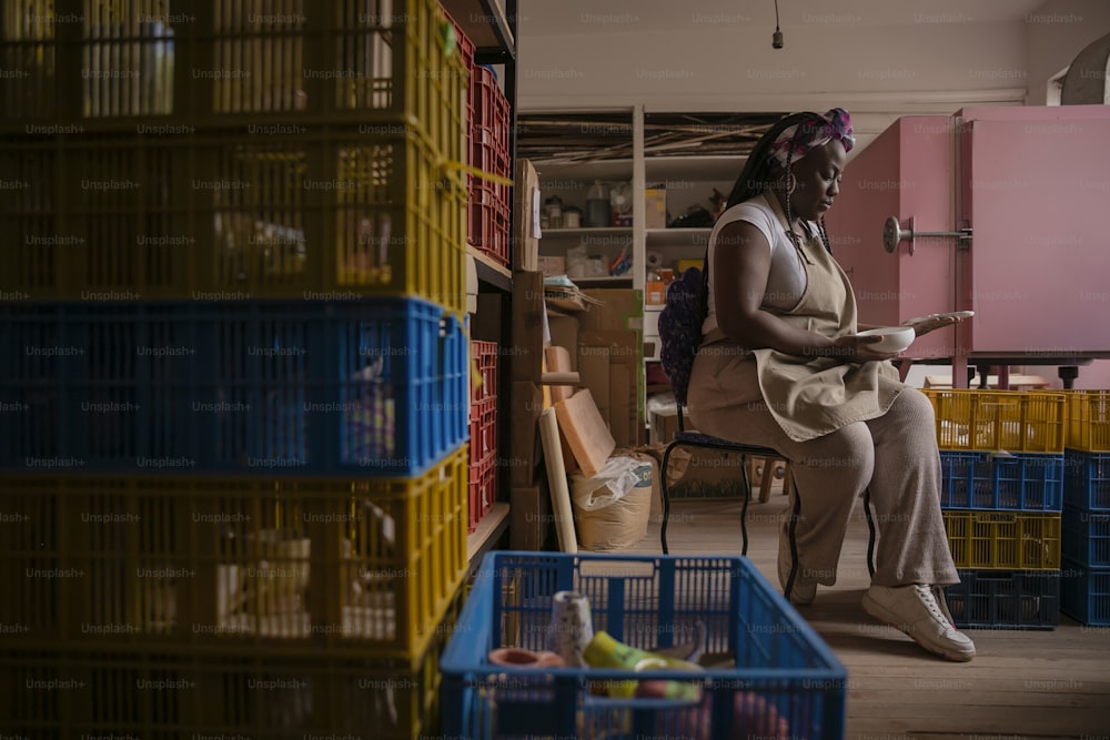 a woman sitting on a chair in a room filled with crates