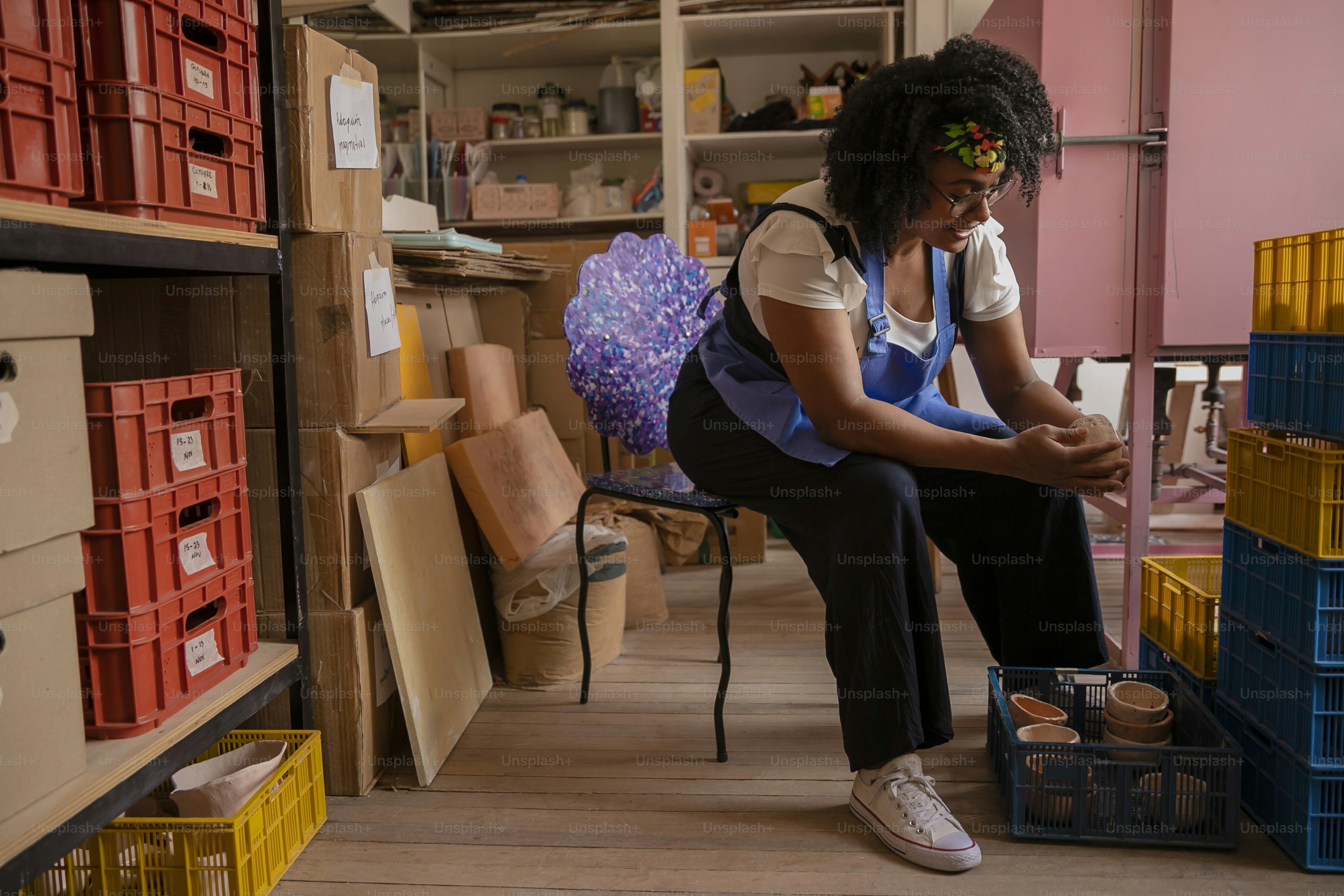 a woman sitting on a chair in a room filled with boxes