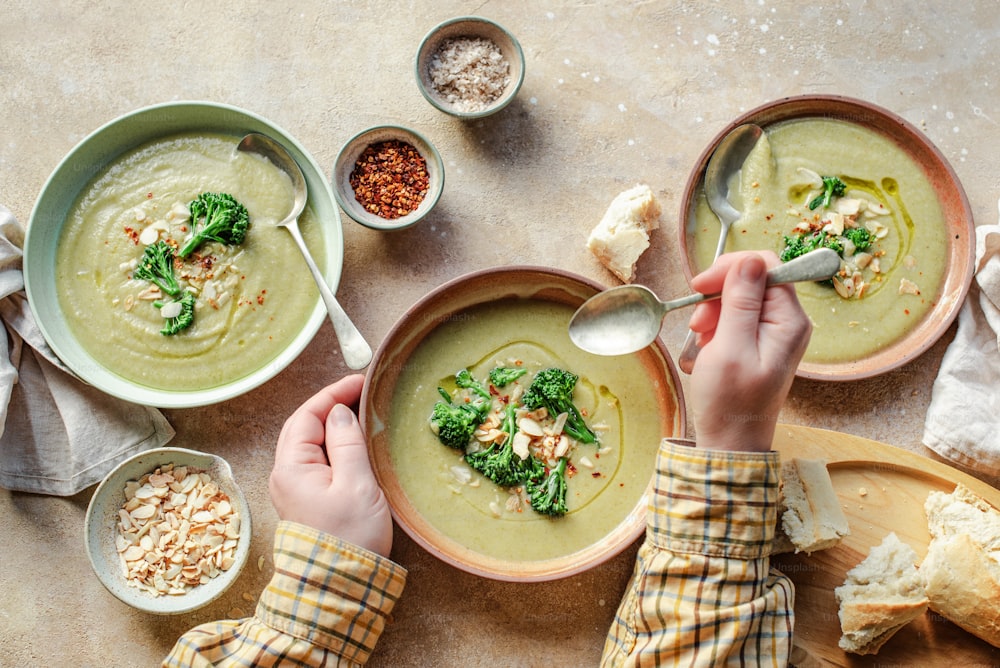 duas tigelas de sopa com brócolis e outros alimentos