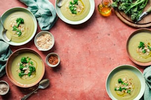 a table topped with bowls of soup and bowls of broccoli