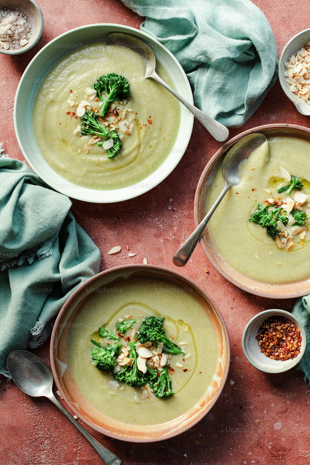 three bowls of soup with broccoli and other toppings