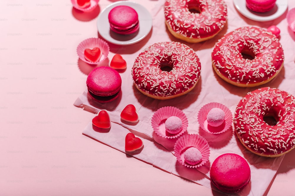 a table topped with donuts covered in pink frosting