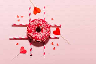 a donut with sprinkles and hearts on a stick