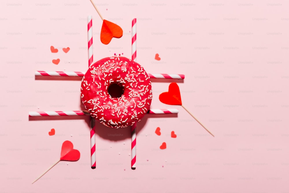 a donut with sprinkles and hearts on a stick