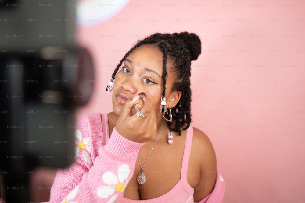 a woman in a pink shirt is brushing her teeth