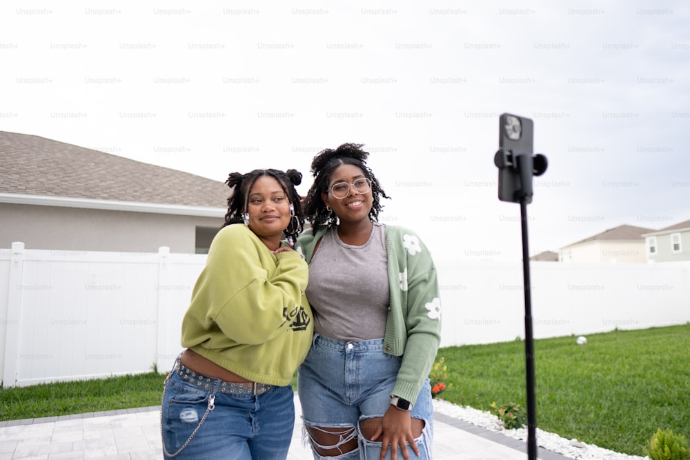 two women standing next to each other in front of a house