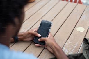 una persona sentada en un banco usando un teléfono celular