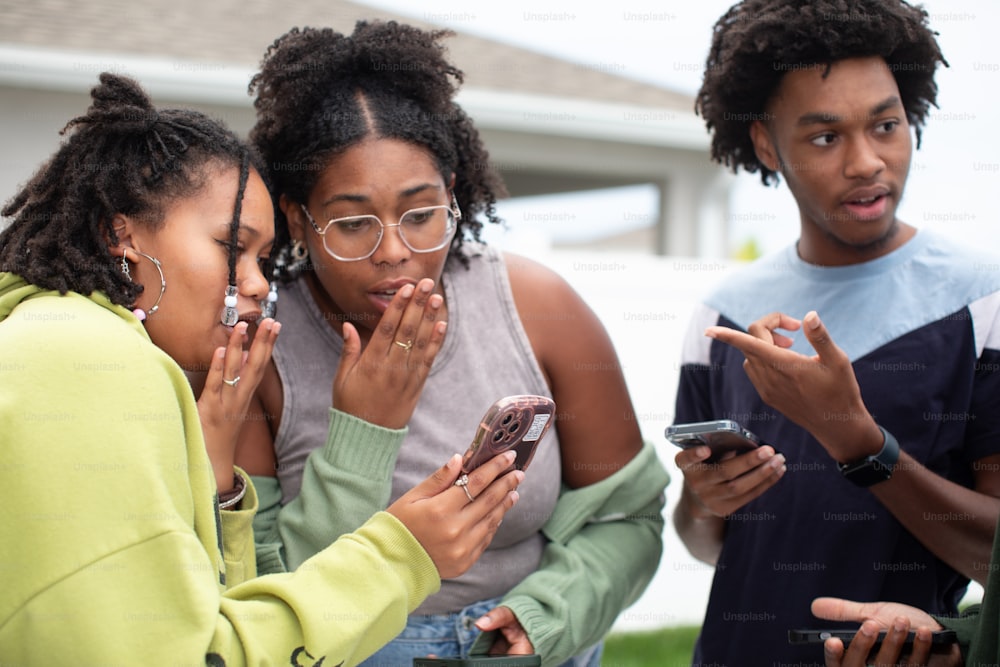 a group of people standing around each other looking at a cell phone