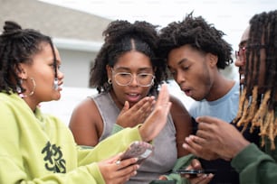 a group of people standing around each other looking at a cell phone