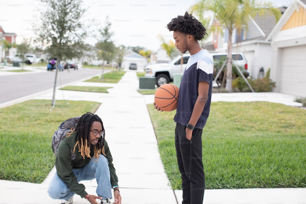 a man holding a basketball next to another man on a sidewalk