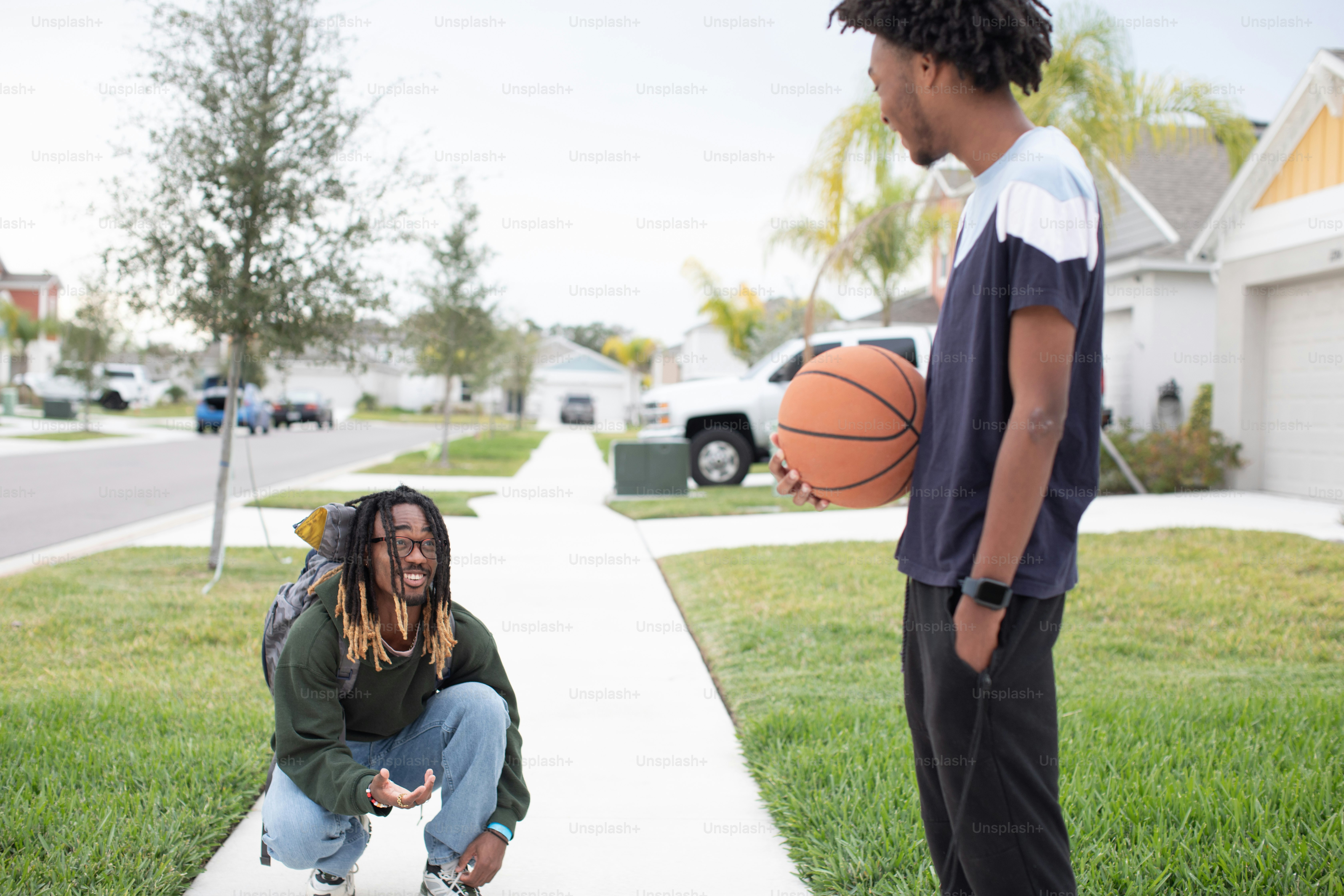 a young man holding a basketball next to another young man