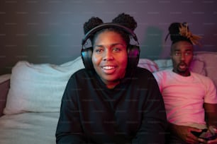 a man and a woman sitting on a bed with headphones on