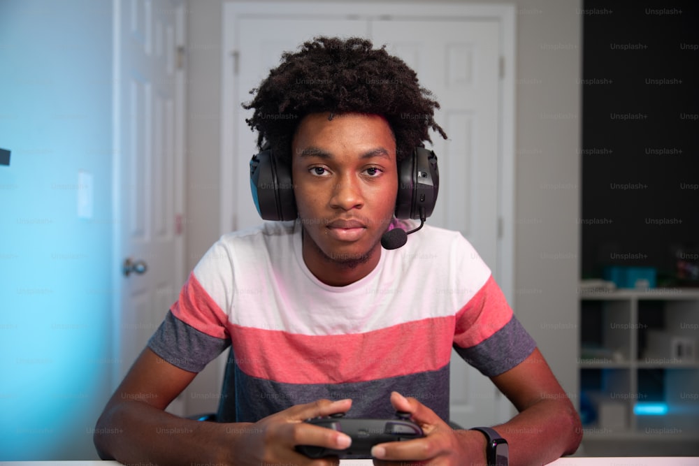 ヘッドフォンを装着し、ビデオゲームのコントローラーを持つ若い男性