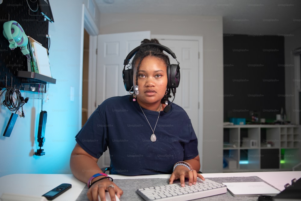 eine Frau sitzt mit Kopfhörern an einem Schreibtisch