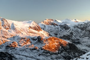 a mountain range covered in snow under a blue sky