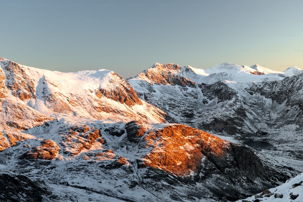 a mountain range covered in snow under a blue sky