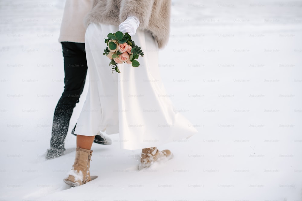 a bride and groom holding hands in the snow